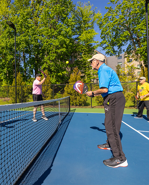 Senior men playing pickleball on an outdoor court