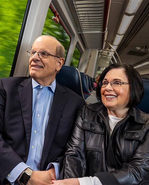 Senior couple holding hands while riding a transit train