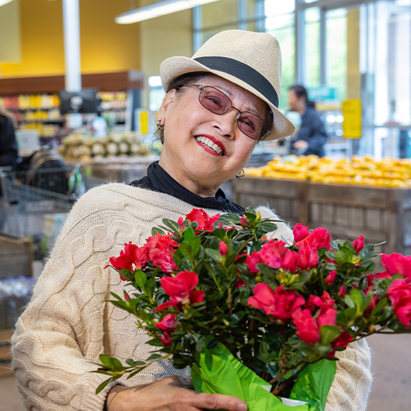 Senior woman buying red flowers at the store