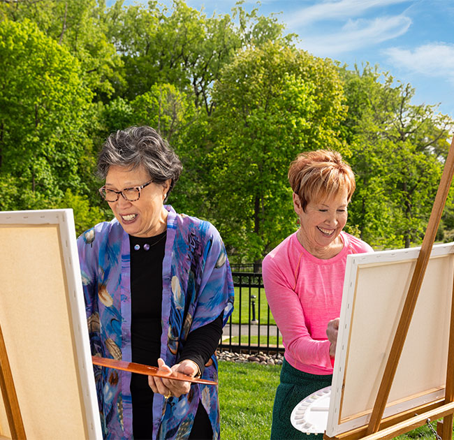 Two senior women painting outdoors
