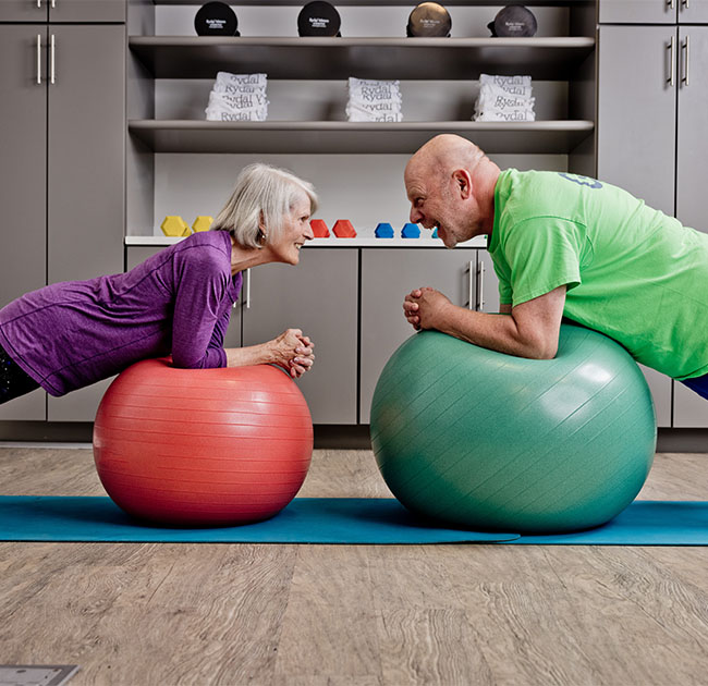 Senior man and senior woman using exercise balls in a fitness center
