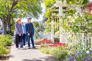Group of senior friends walking down the sidewalk and looking at flowers