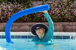 Senior woman using foam pool noodle in the pool at The Terraces at Los Altos