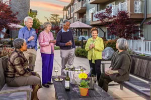 Six seniors drinking wine and chatting on an outdoor patio at The Terraces at Los Altos