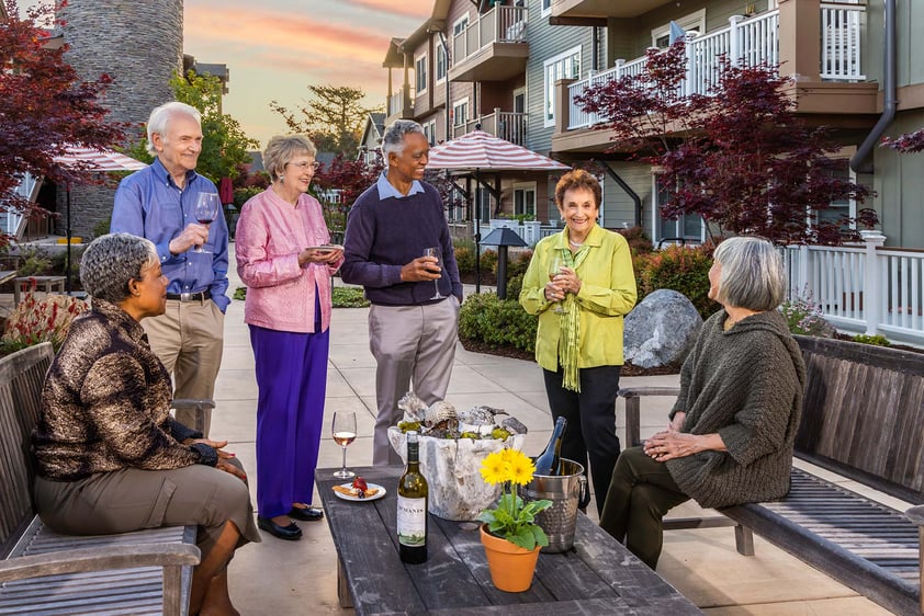 Six seniors drinking wine and chatting on an outdoor patio at The Terraces at Los Altos