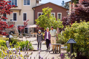 Two senior women and a senior man walking through the grounds of The Terraces at Los Altos