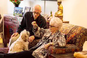 Senior couple sitting with their small dog in their apartment at The Terraces at Los Altos