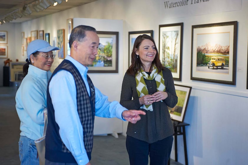 Senior couple at an art gallery talking with a gallery employee