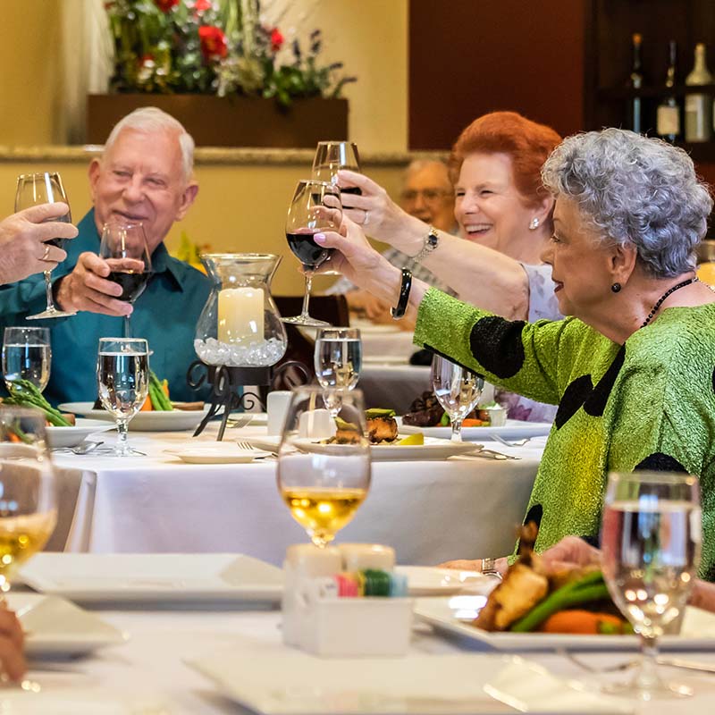 Seniors in a restaurant toasting each other with glasses of wine