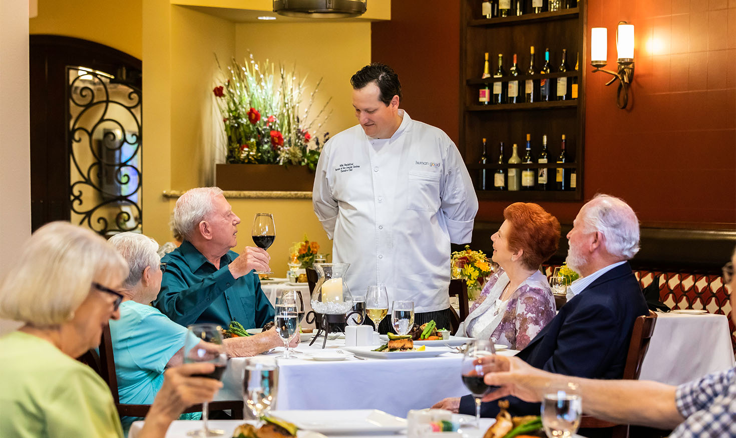 Group of seniors dining while talking to the chef