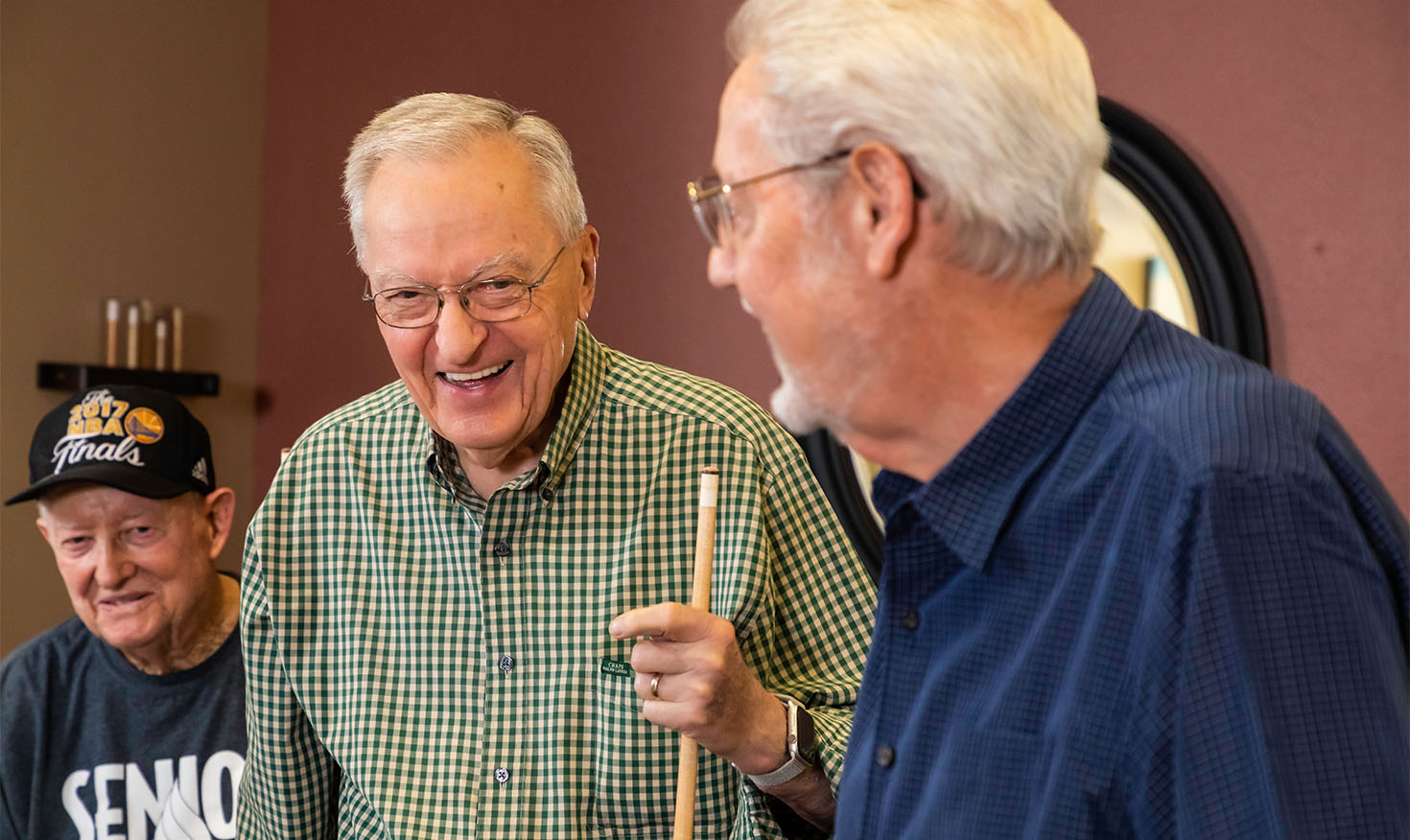 Three senior men playing a game of pool