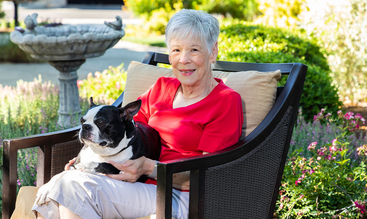 Senior woman sitting outside with a small black-and-white dog in her lap