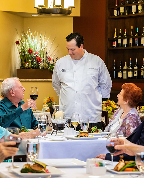 Group of seniors dining while talking to the chef