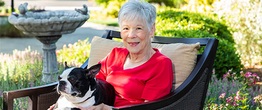 senior woman sitting outside with dog in her lap