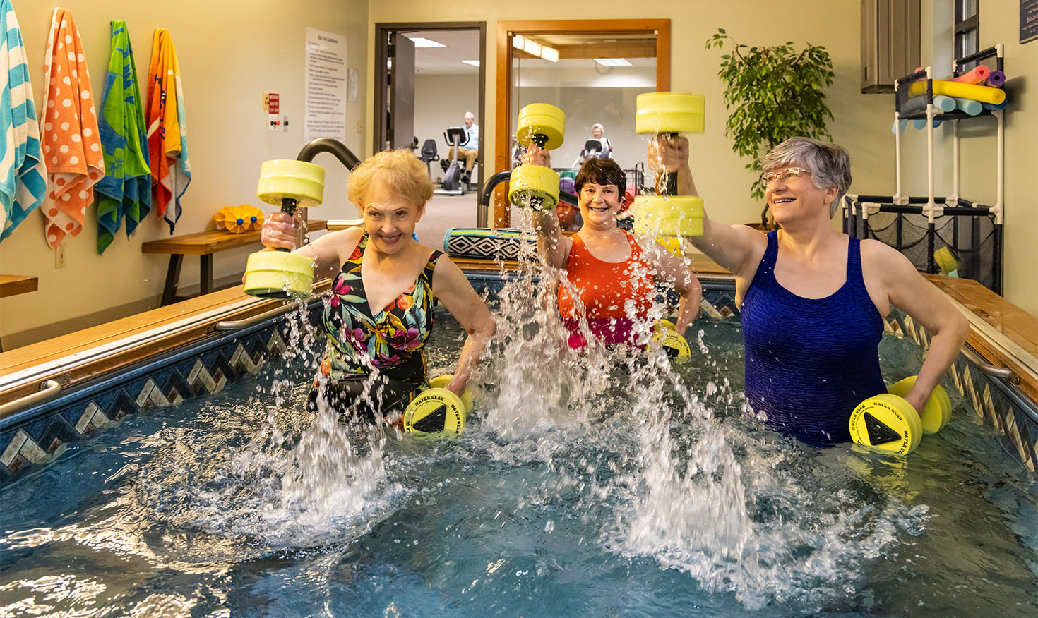 Three senior women using water weights in a water exercise class