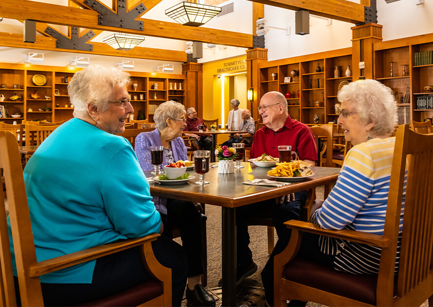 Group of four seniors eating dinner in the dining room at The Terraces of Summitview