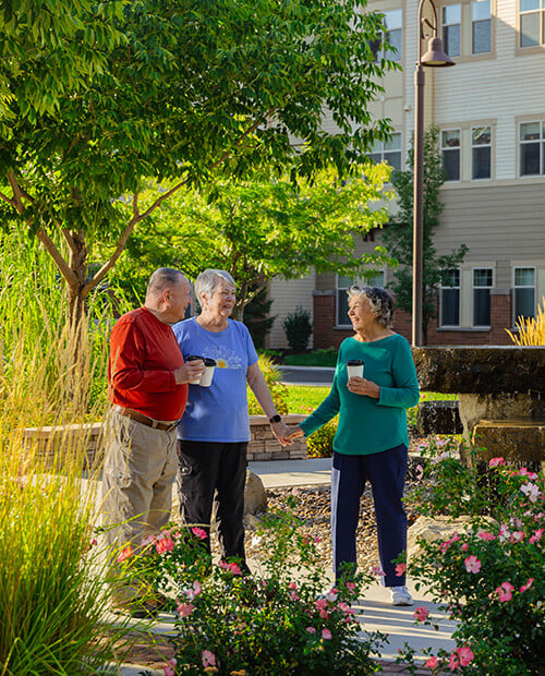 Senior man and two senior women drinking coffee and talking outdoors at The Terraces of Boise