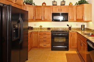 Kitchen with wood cabinets, granite countertops and black appliances in an apartment at The Terraces of Boise