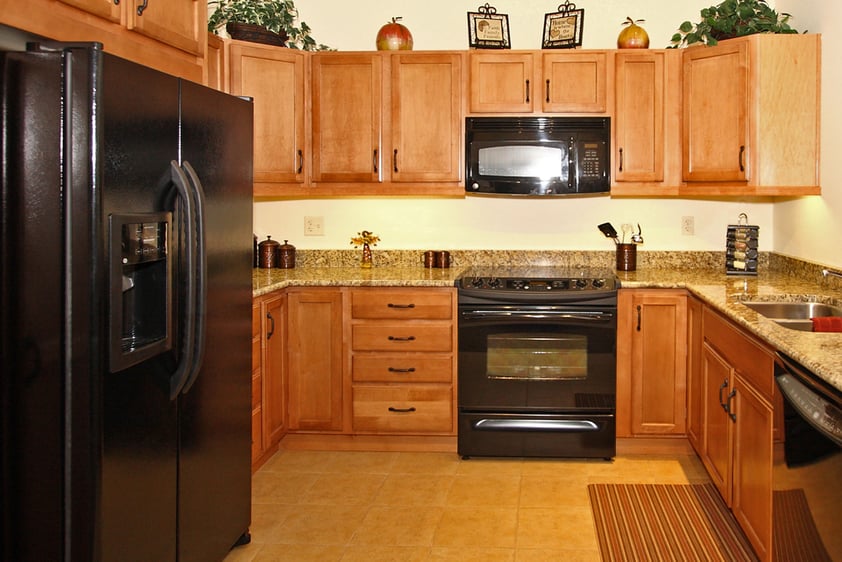 Kitchen with wood cabinets, granite countertops and black appliances in an apartment at The Terraces of Boise
