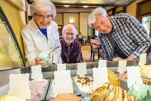 Two senior men and a senior woman looking at the gelato flavors in the bistro at The Terraces of Boise