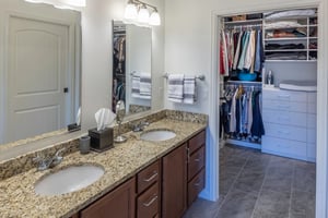Bathroom featuring a vanity with two sinks and a walk-in closet in an apartment at The Terraces of Boise