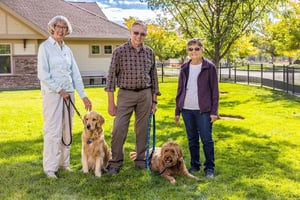 Two senior women and a senior man with two dogs standing in the dog park at The Terraces of Boise
