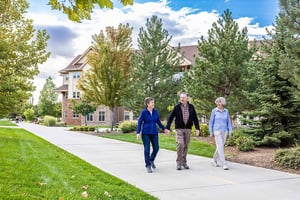 Senior couple holding hands and walking next to a senior woman through The Terraces of Boise