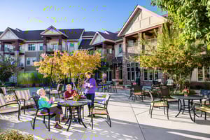 Three senior friends with coffee around a patio table at The Terraces of Boise