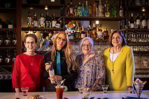 Three senior women and a female mixologist at a bar during a cocktail making class