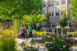 Senior woman standing and talking to a senior couple sitting in a garden at The Terraces of Boise