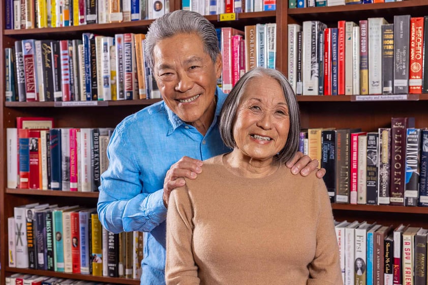 Senior man with his hands on the shoulders of a senior woman in a library