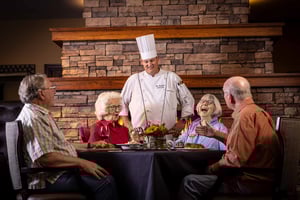 Chef chatting with a group of four seniors dining in The Terraces of Boise dining room