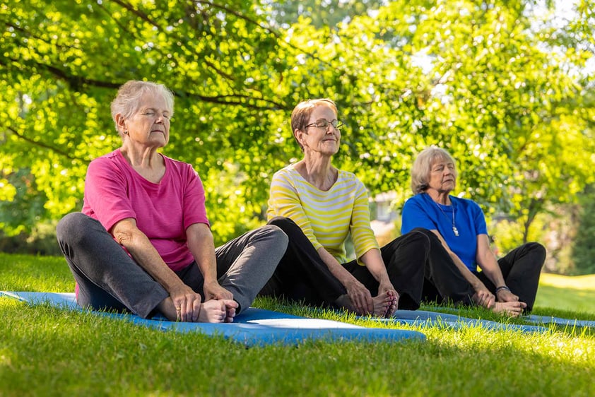 Three senior women doing yoga on the lawn of The Terraces of Boise