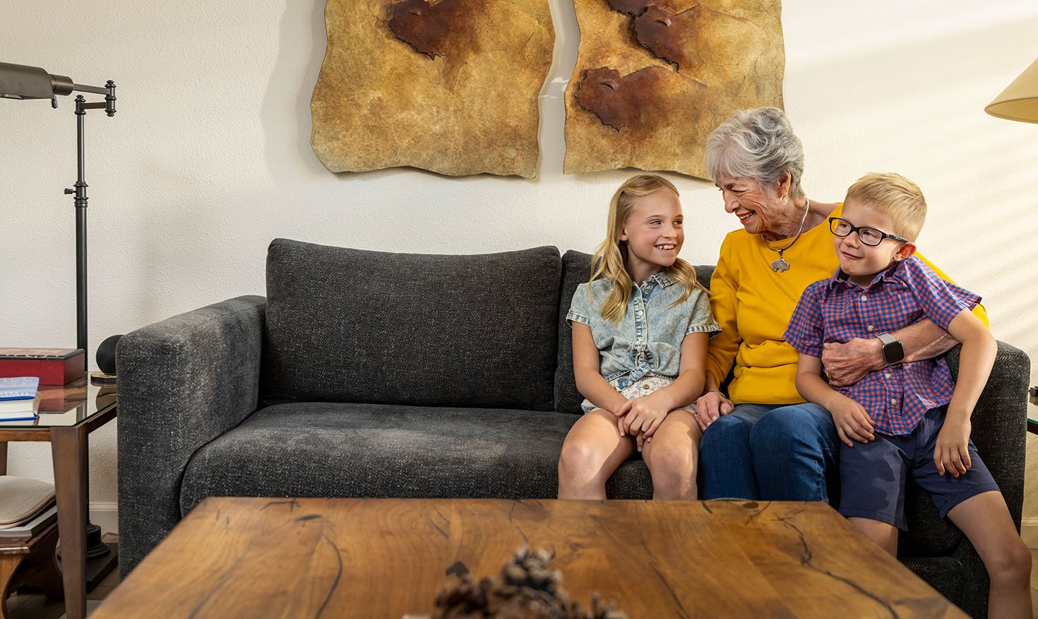 Senior woman sitting on a couch with her young granddaughter and grandson