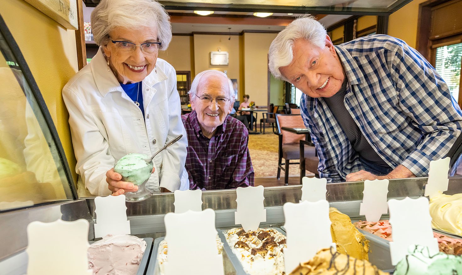 Two senior men and a senior woman looking at the gelato flavors in the bistro at The Terraces of Boise