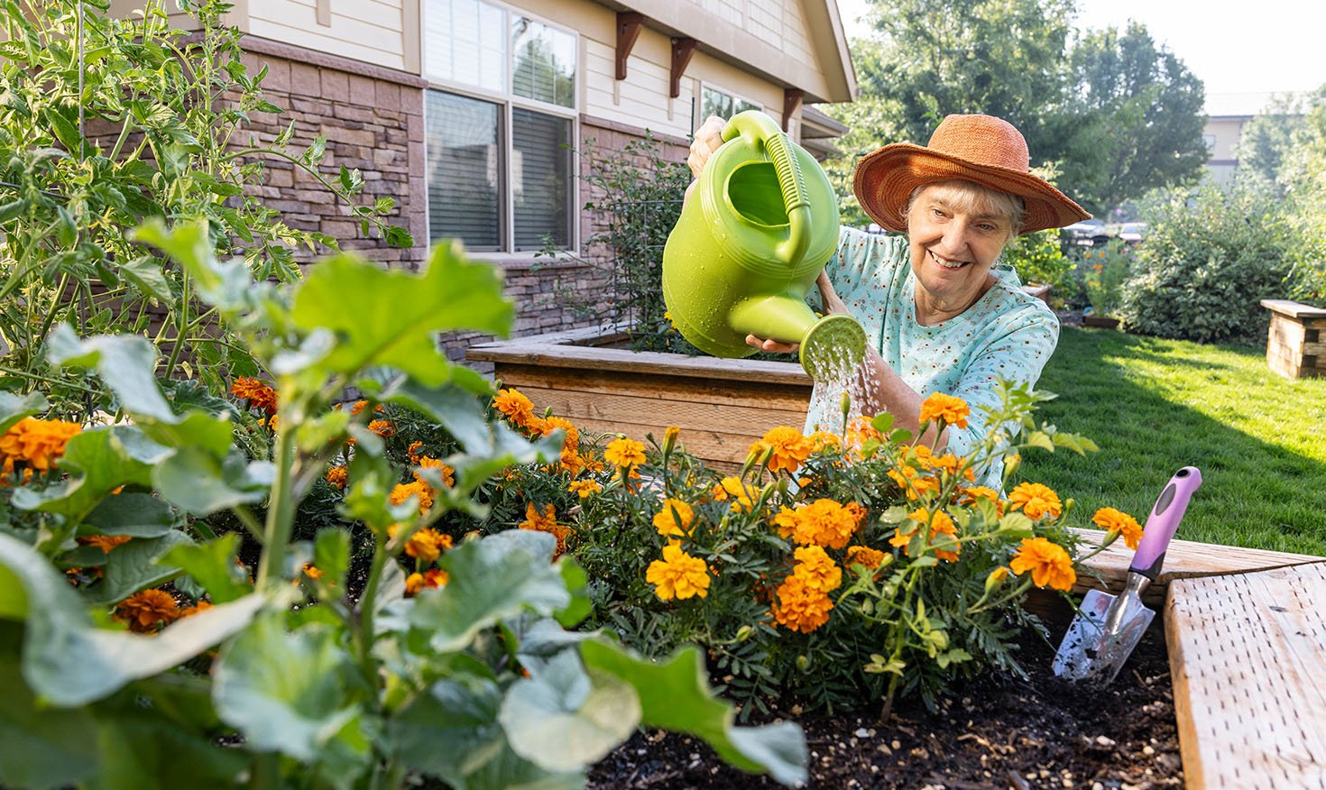 Senior women in a sun hat watering her flowers