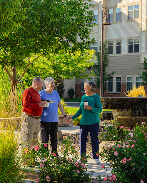 Senior man and two senior women drinking coffee and talking outdoors at The Terraces of Boise