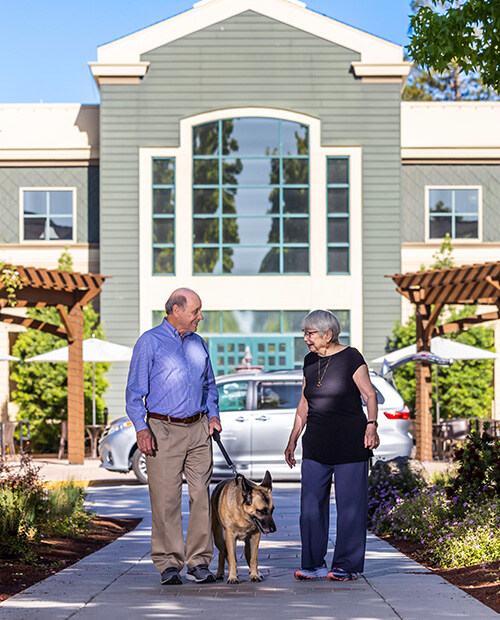 Senior couple walking a German shepherd outside The Terraces of Los Gatos