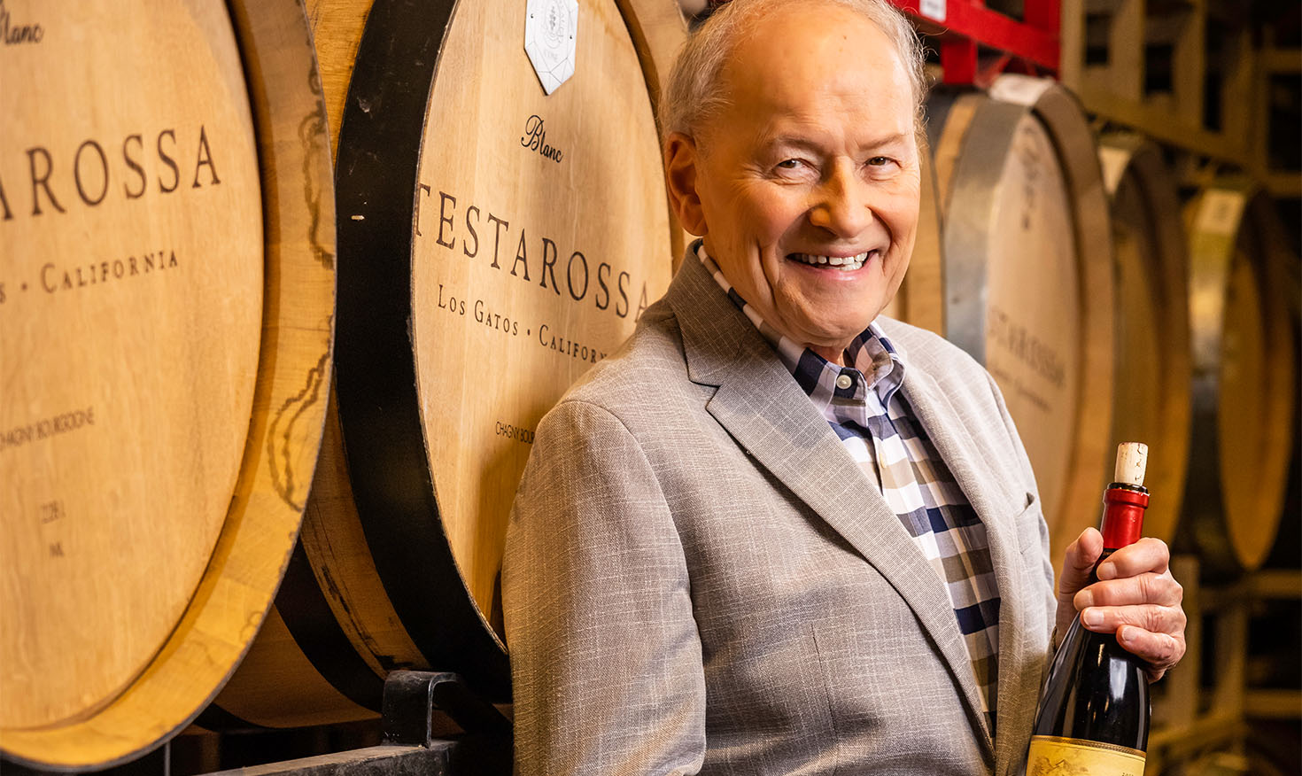 Senior man holding a wine bottle in a wine cellar
