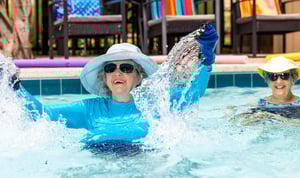 Senior woman wearing a sun hat doing water aerobics in an outdoor pool