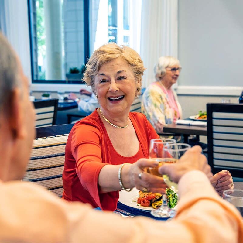 Seniors clinking glasses of wine in the main dining room of The Terraces of Los Gatos