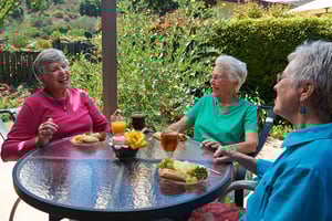 Three senior women having lunch at an outdoor table and talking