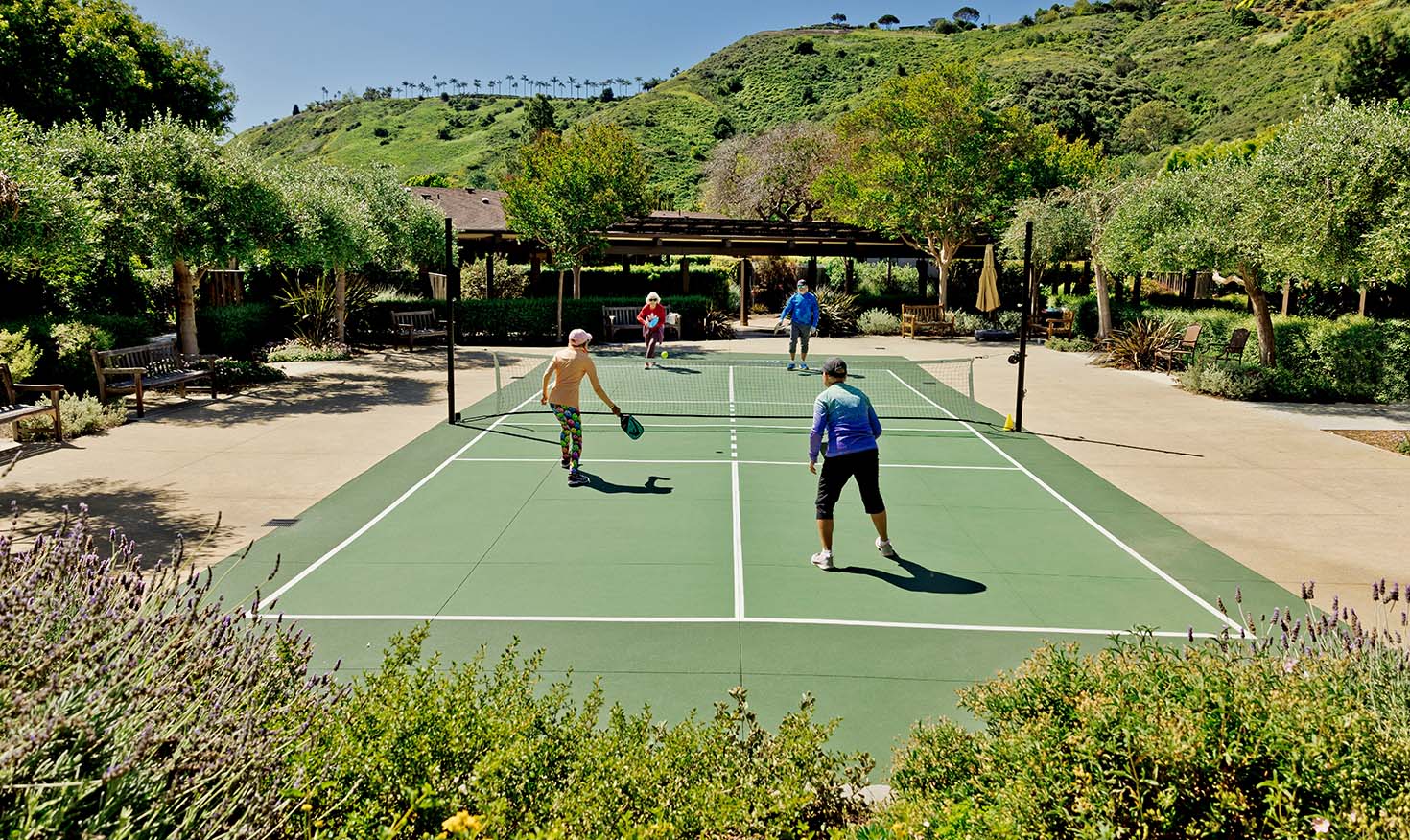 Four seniors playing pickleball on an outdoor court at Valle Verde