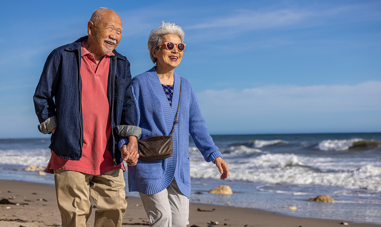 Senior couple holding hands and walking on the beach