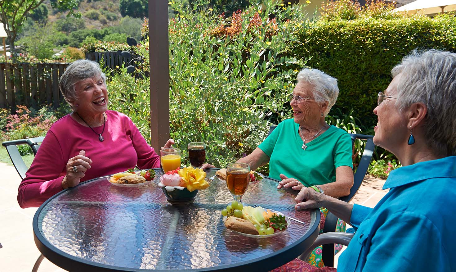 Three senior women having lunch at an outdoor table and talking