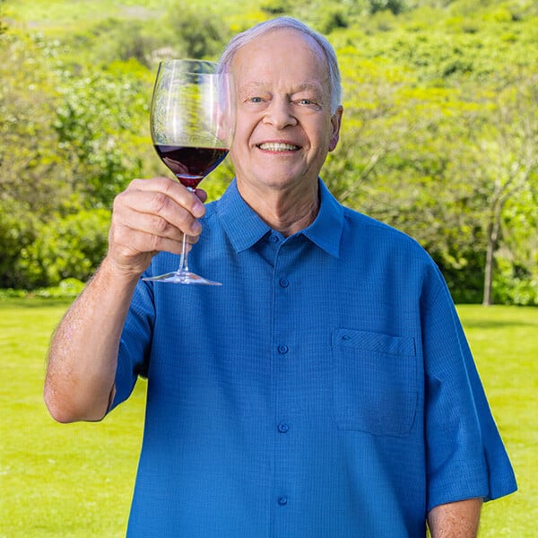 Senior man standing outside and holding up a glass of red wine