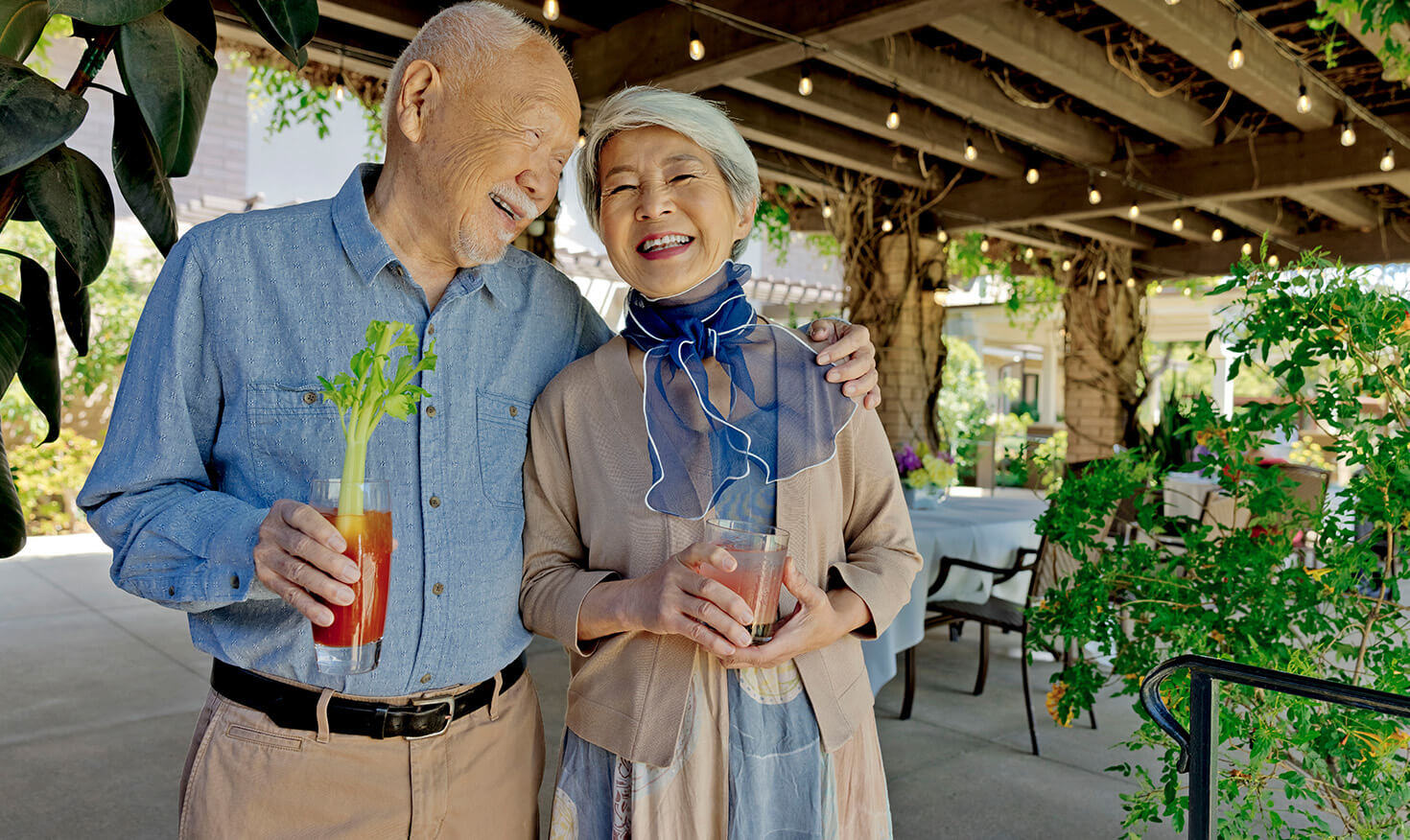 Senior couple holding drinks and standing on a patio
