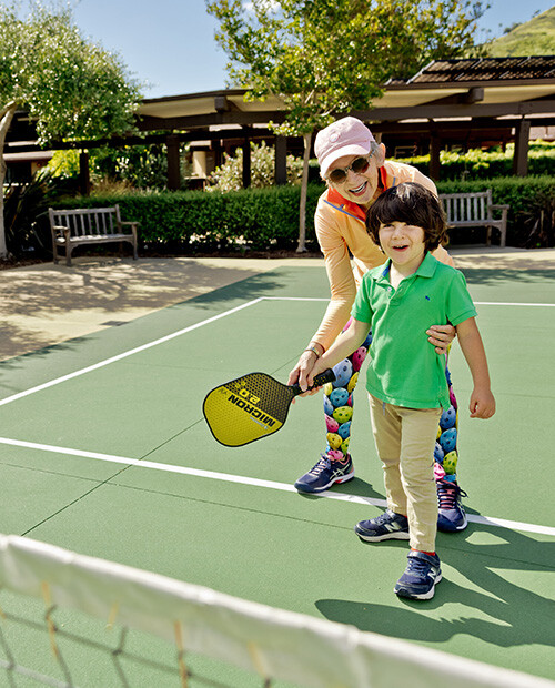 Senior woman showing a male child how to play pickleball