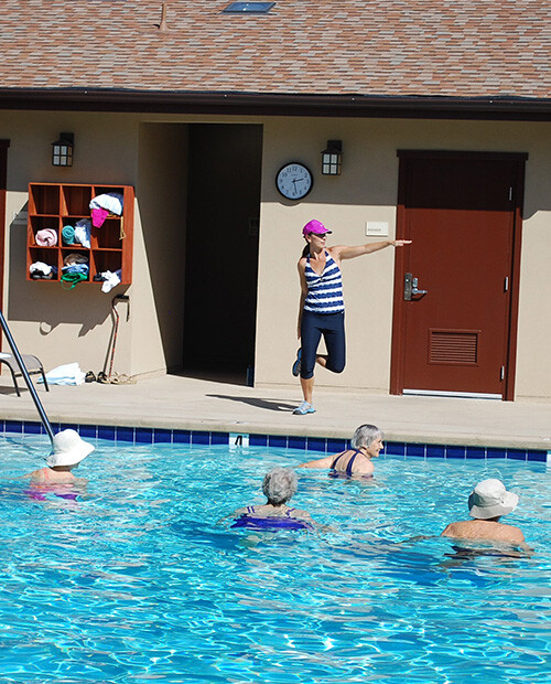 Group of seniors in a water aerobics class in the outdoor pool with instructor