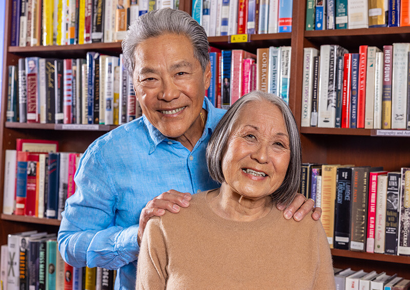 Senior man with his hands on the shoulders of a senior woman in a library
